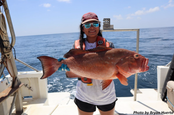 A girl holding a large red fish.